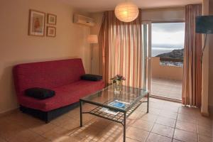 卡塔赫纳Camping Naturista El Portús - Nudist FKK的客厅配有红色的沙发和玻璃桌