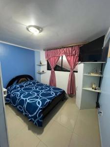 AtuntaquiHermoso y acogedor departamento的一间卧室设有蓝色的床和窗户。
