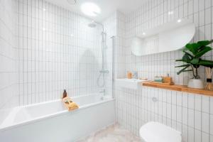 伦敦Luxurious two-bedroom flat with scenic views的白色瓷砖浴室设有浴缸和水槽