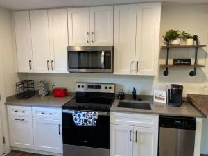 格林维尔Charming 2Br, Fully Equipped kitchen, Smart TV的厨房配有白色橱柜和黑炉灶烤箱。