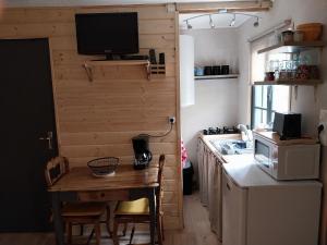 Saint-AubanPetit studio dans la prairie的一个带桌子的小厨房和墙上的电视