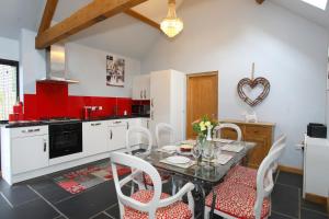 阿什伯恩Woodshed Cottage的一间带桌椅的厨房和一间带红色调的厨房