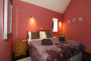 阿什伯恩Woodshed Cottage的卧室设有红色的墙壁和一张大床