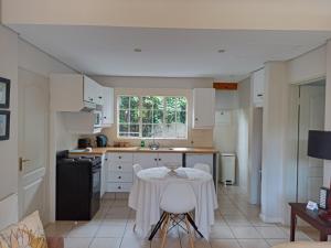 约翰内斯堡Darrenwood Guesthouse & SPA的厨房配有桌子和白色橱柜。