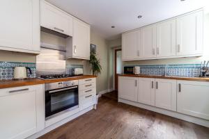 伦敦The Queenstown Villa的白色的厨房配有白色的橱柜和木地板。