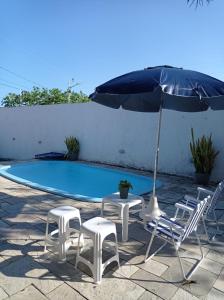 雅克南Casa de praia em Carapibus的一组椅子和一把遮阳伞,位于游泳池旁