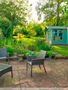惠特彻奇Portland House的一个带椅子的庭院和一个带蓝色房子的花园