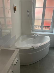 维希Hôtel & Restaurant Le Patio VICHY的带窗户的浴室内的白色浴缸