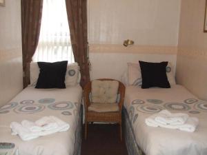 布莱克浦Fern Villa Hotel - Albert Road的客房设有两张单人床和一把椅子。