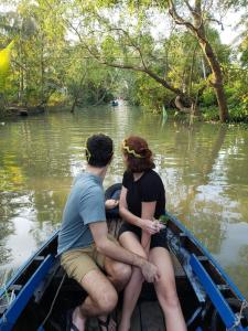 Bình ThủyCan Tho Riverside Hostel的坐在水面上船中的男人和女人