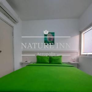 当格浪Barata Hotel by Nature's的一间卧室配有一张绿色的床,并带有瑙里尔旅馆标志