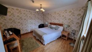 LlanyreBell Country Inn的卧室配有白色的床和花卉壁纸