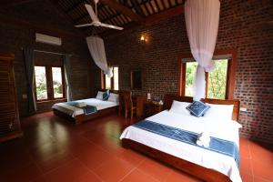 宁平Phạm Gia Homestay Ecogarden的一间卧室设有两张床和砖墙