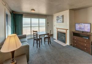 洛克威海滩冲浪度假酒店的客厅配有沙发和带壁炉的桌子