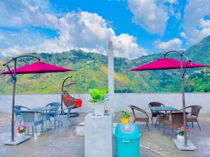 穆索里River Grand Resort - A Peaceful Stay Kempty Fall Mussoorie的一组桌椅和红色遮阳伞