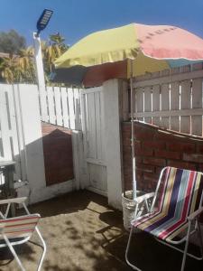黑岛El Refugio de la Estancia的庭院配有两把椅子和一把遮阳伞