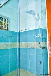 KisiiThe Mevrose Resort的浴室设有玻璃淋浴间,铺有蓝色瓷砖