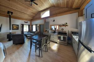 Whale Pass Adventure Cabin的厨房以及带桌子和冰箱的客厅。