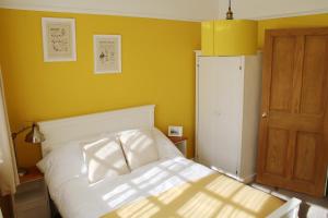 阳光港Charming 1800s Port Sunlight Worker's Cottage的卧室配有白色的床和黄色的墙壁