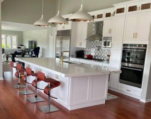 海兰帕克2-Acre Highland Park Retreat with Heated Pool ~ 5*的厨房配有白色橱柜和带红色椅子的柜台。