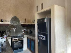 拉穆Umma House的厨房配有黑色冰箱和炉灶。