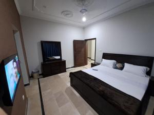 伊斯兰堡Islamabad Layover Guest House Free Airport Pick and Drop的一间卧室配有一张床和一台平面电视