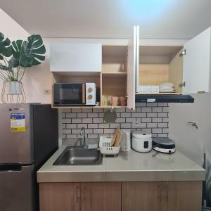 达斯马里尼亚斯HOMELY @ Green 2 Residences SMDC DLSUMC的厨房配有水槽和微波炉