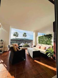 圣罗克Feel The Vibe Alcaidesa的一间带两张沙发的客厅和一个带棕榈树的阳台