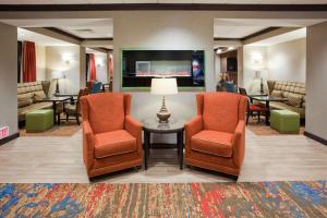 罗斯维尔明尼苏达州罗斯维尔明尼阿波利斯汉普顿酒店的一间设有两把椅子和一张桌子的等候室以及一台电视