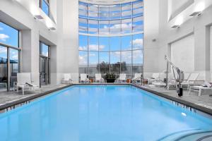 休斯顿凯蒂希尔顿合博套房酒店的一座带窗户的建筑里,有一个蓝色的游泳池
