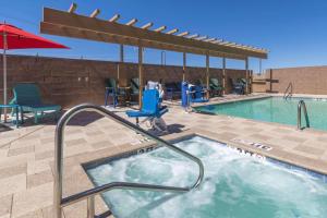 金曼金曼希尔顿欣庭套房酒店的游泳池设有热水浴池、椅子和遮阳伞