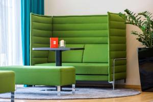 纽伦堡纽伦堡雷迪森公园客栈的一张绿色沙发,位于带桌子的房间