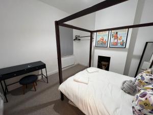 曼彻斯特Altrincham Terrace - 2 Bedroom House - Free Parking - Sleeps 6 - Near Tram Stop的一间卧室配有一张床、一张桌子和一张四柱床。