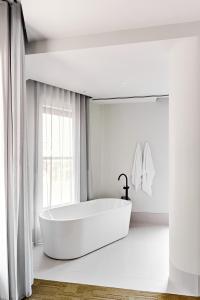 墨尔本Central Club Hotel - North Melbourne的白色的浴室设有浴缸和窗户。