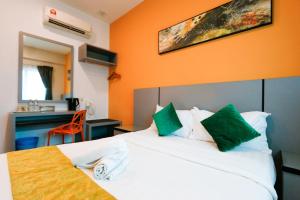 怡保旅悦酒店的配有白色床和绿色枕头的酒店客房