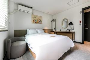 庆州Hotel No. 25 Gyeongju bus terminal的卧室配有一张白色大床和一把椅子