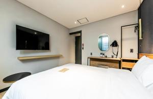 庆州Hotel No. 25 Gyeongju bus terminal的卧室配有一张白色大床和一张书桌