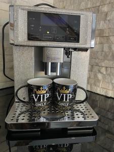 温特贝格VIP Haus Winterberg的咖啡机、两个咖啡杯和电视