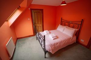 巴拉胡利什Woodlands House的一间卧室拥有橙色的墙壁,床上铺有白色的床单。
