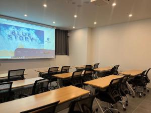 釜山Haeundae Blue Story Hotel的配有桌椅和投影屏幕的教室
