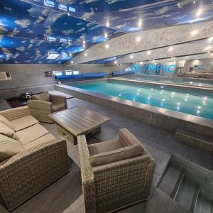 贝尔格莱德Olympic Apartments Wellness & Spa的一个带藤椅和桌子的游泳池以及游泳池