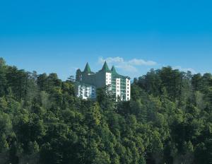 西姆拉欧贝罗伊塞西尔酒店的一座树冠茂密的山顶上的建筑