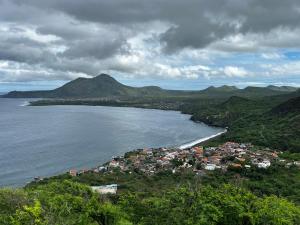 Ribeira da PrataDunas De Areia Preta的水中的一个岛屿,有房子和山