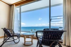 别府Spa and Resort Hotel Solage Oita Hiji Beppuwan的客房设有椅子和海景大窗户。