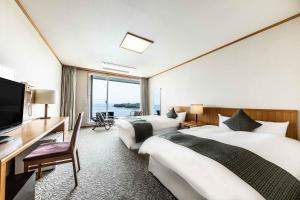 别府Spa and Resort Hotel Solage Oita Hiji Beppuwan的酒店客房设有两张床、一张桌子和一台电视。