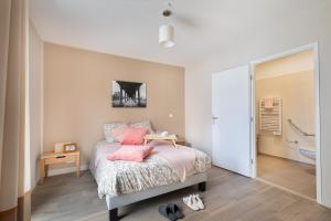 Le RaincyZenao Appart'hôtels Le Raincy的一间卧室配有带粉红色枕头的床和一间浴室