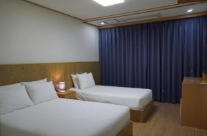 西归浦市Soldongsan Stay的酒店客房带两张床和蓝色窗帘