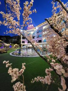 Cham Ta LaoHeaven Hill Hotel & Hot Spring的一座有喷泉和白色花树的建筑
