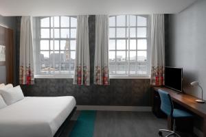 利物浦Aloft Liverpool的一间卧室配有一张床、一张书桌和两个窗户。