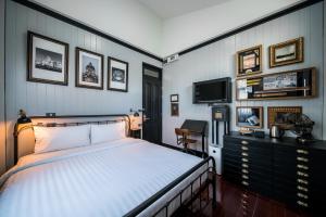 曼谷DE Phanakron Boutique Hotel的一间卧室配有一张床、一张书桌和一台电视。
